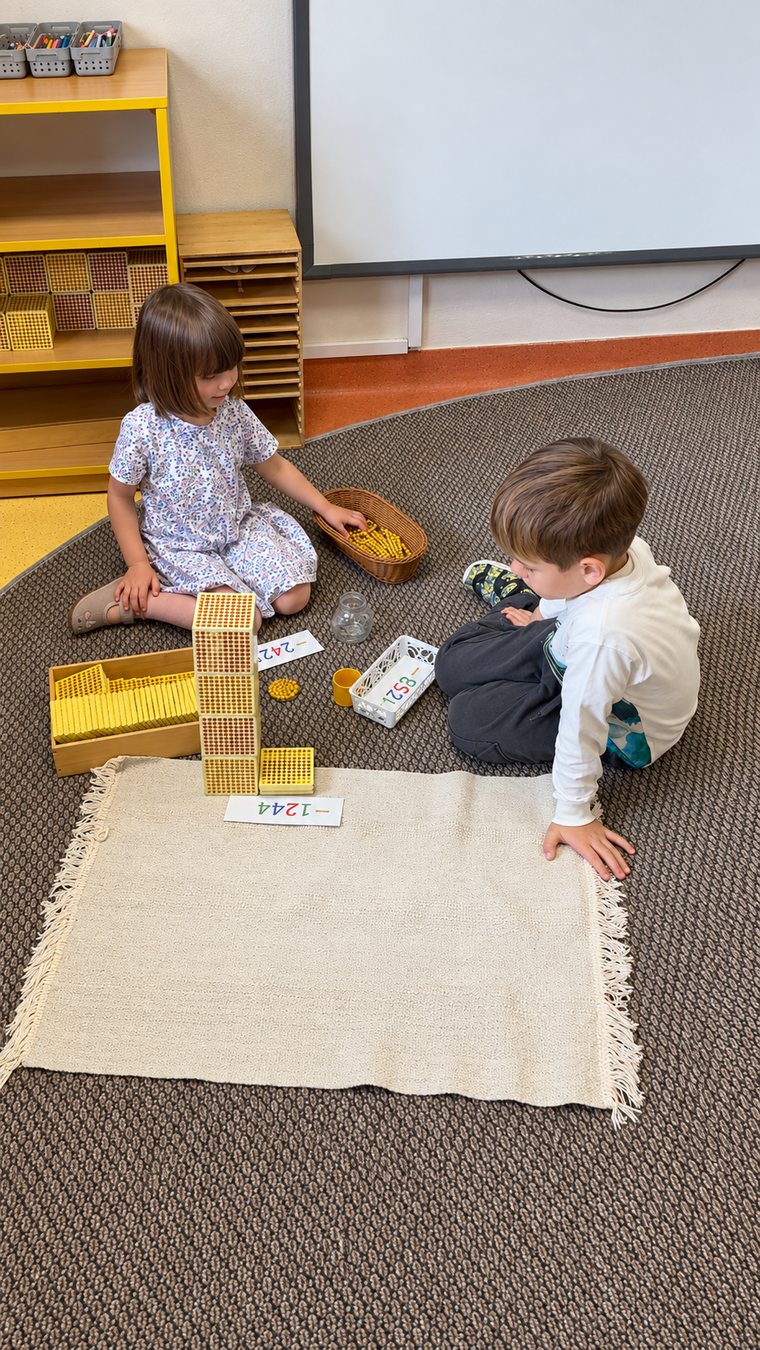 Dzieci pracujące ze złotymi perłami Montessori na dywanie
